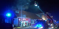Feuerwehrleute löschen aus dem Korb einer Drehleiter heraus den Brand in einem Restaurant.