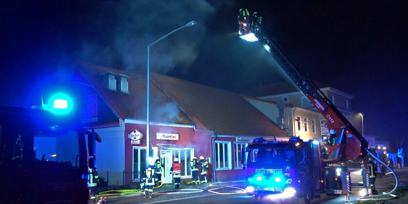 Feuerwehrleute löschen aus dem Korb einer Drehleiter heraus den Brand in einem Restaurant.