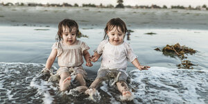 Zwei kleine Mädchen - Zwillinge sitzen im Meer