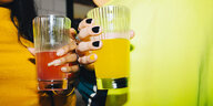 Zwei Hände mit lackierten Fingernägeln halten jeweils ein Getränk