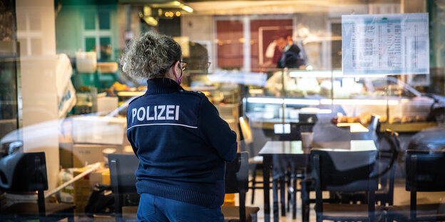 Eine Polizistin steht vor dem Fenster eines Restaurants
