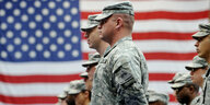 US-Soldaten stehen stramm in einer Reihe vor der US-Flagge.