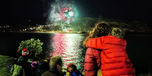Eine Gruppe schaut über das Wasser auf das Feuerwerk