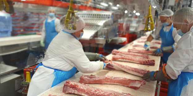 Schlachthof-Mitarbeiter verarbeiten Fleisch am Fließband.