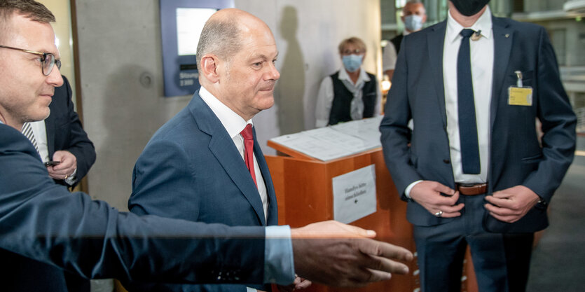 Olaf Scholz läuft an zwei Männern vorbei.