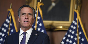 Mitt Romney steht vor US-Flaggen.