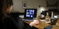 Eine Frau sitzt während der Corona-Pandemie an einem Tisch in ihrer Wohnung vor einem Laptop, während sie mit weiteren fünf Personen an einer Videokonferenz mit der Videokonferenzanwendung ZOOM teilnimmt