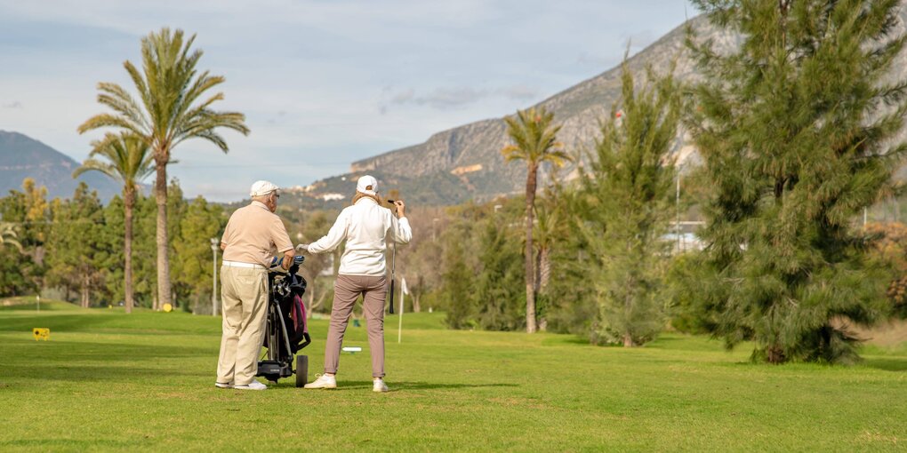 Ein älteres Pärchen auf einem Golfplatz unter Palmen