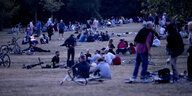 Menschen sitzen nachts im Volkspark Hasenheide auf einer Wiese und machen Party – ein Foto von Anfang Juli