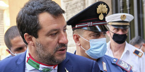 Matteo Salvini und Sicherheitsbeamte mit Mundschutz.