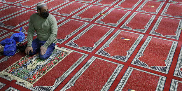 Ein gläubiger sitzt auf einen Gebetsteppich in einer leeren Moschee