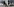 Ein Mann mit Mundschutz geht an einer Bretterwand mit den Fotos zwei Verhandler vorbei