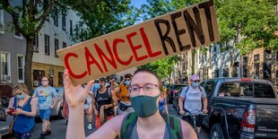 Eine Frau mit Mundschutz hätl auf einer Demonstration ein selbstgemaltes Schildmit der Aufschirft: Cancel Rent