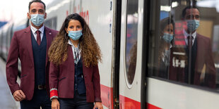 Zwei Zugbegleiter stehen in der neuen Bekleidung der Deutsche Bahn neben einem ICE