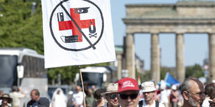 Protestplakat, auf dem ein zu einem Hakenkreuz erweitertes rotes Kreuz zu sehen ist