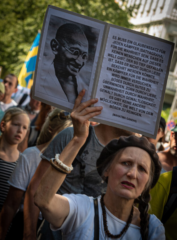 Eine Frau hält ein Bild von Gandhi und ein Gandhi-Zitat hoch Eine Frau hält ein Bild von Gandhi und ein Gandhi-Zitat hoch