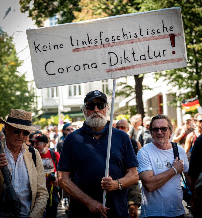 Ein Mann hält ein Plakat mit der Aufschrift "Keine linksfaschistische Corona-Diktatur"