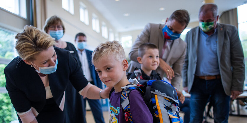 Franziska Giffey mit Maske beugt sich zu einem Schüler herab