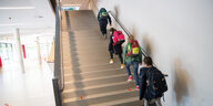 Kinder mit Rantzen gehen Treppe hoch