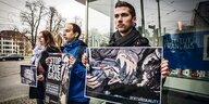 Drei Aktivisten der Organisation „Animal Equality“ halten Protestplakate in die Luft.