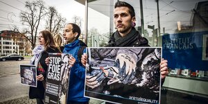 Drei Aktivisten der Organisation „Animal Equality“ halten Protestplakate in die Luft.