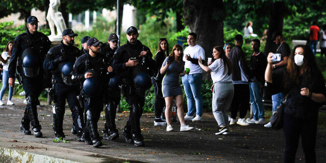 jugendliche im Schlossgarten. Eine Polizeigarde läuft vorbei