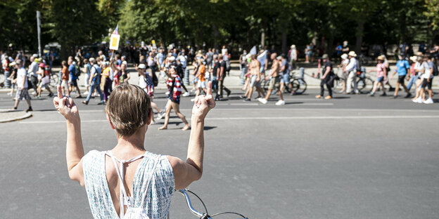 Eine Frau zeigt einer demonstrierenden Menschenmenge ihre Mittelfinger