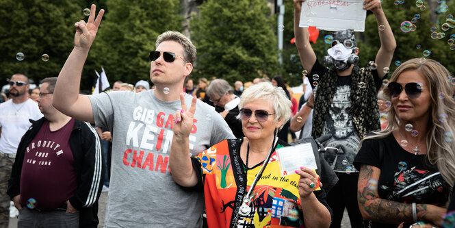 Menschen ohne Gescihtsmaskestehen vor im Lustgarten in Berlin und demonstrieren gegen die New World Order