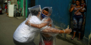 Zwei Menschen umarmen sich eingehüllt in Plastiksäcken