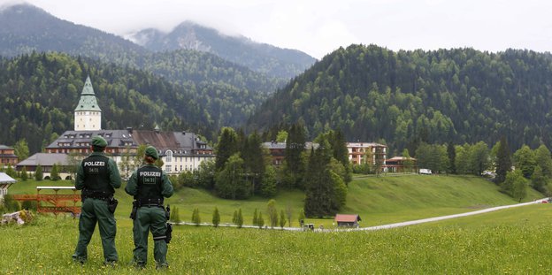 Zwei Polizisten blicken auf Schloss Elmau