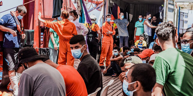 Eine Personengruppe auf einem Schiff mit Mundschutzmasken