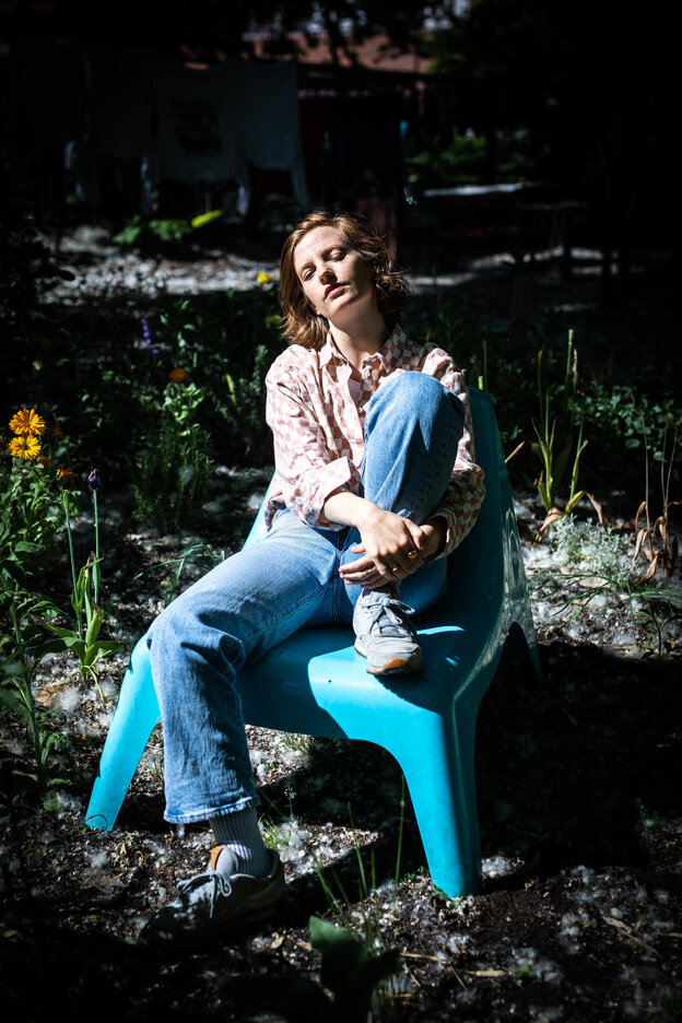 Sängerin Wilhelmine ist in einem besetzten Haus in Kreuzberg aufgewachsen. Für die Aufnahme setzte sie sich in den Garten des Hausesauf einen hellblauen Stuhl und guckt verträumt