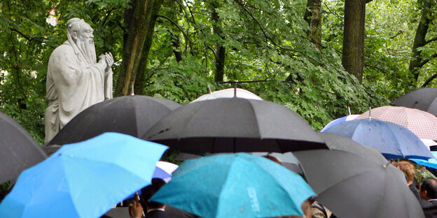 Gäste mit Regenschirmen stehen 2007 in München vor einer gerade enthüllten Konfuzius-Statue