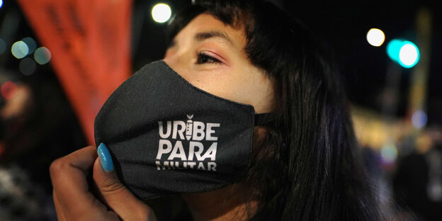 Eine Frau trägt eine Gesichtsmaske mit der Aufschrift "Uribe Paramilitär"