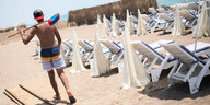 Ein Mann mit einem Besen geht an einem leeren Strand in Antalya entlang