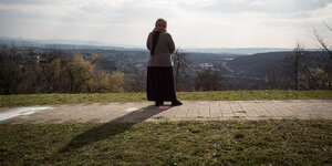 Eine Frau steht mit dem Rücken zum Betrachter und schaut über ein Tal