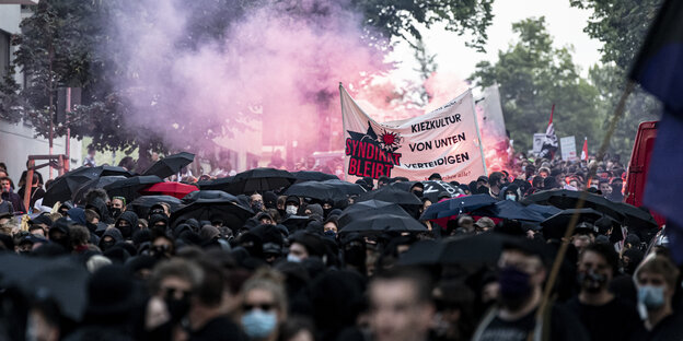 Eine große Demo schwarz gekleideter Menschen zündet Pyrotechnik im Schillerkiez