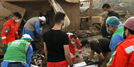 Helfer in orangener Kleidung helfen bei der Bergung von Menschen aus den Trümmern