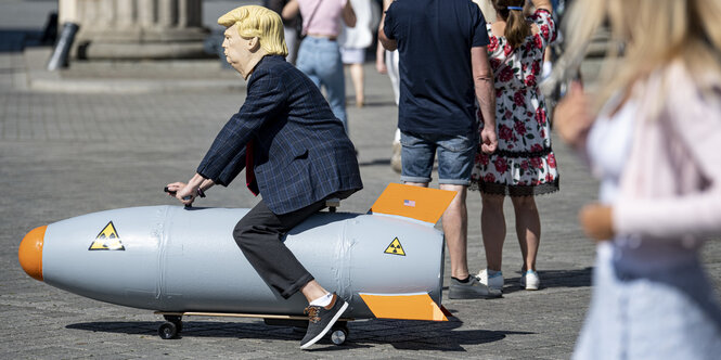 Ein als US-Präsident Trump verkleideter Aktivisten fährt vor dem Brandenburger Tor auf einem fahrbaren Modell einer Atombombe