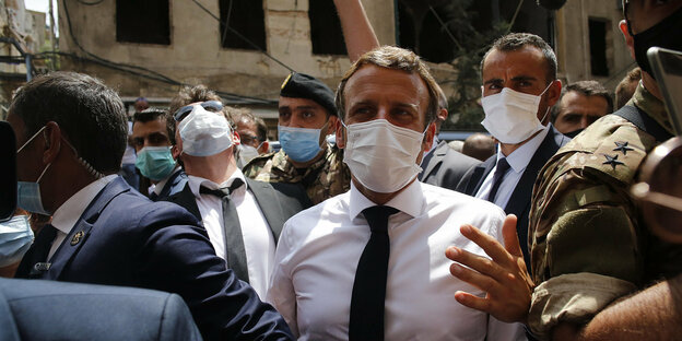 Präsident Macron trägt eine Mundschutzmaske und steht in einer Menschenmenge