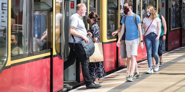 Reisende steigen in die S-Bahn. Ein Fahrgast, der die S-Bahn verlässt, trägt die Schutzmaske unterhalb des Mundes am Kinn