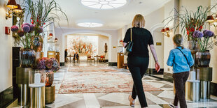 Eine Frau und ein Kind laufen in das schicke Foyer eines Hotels