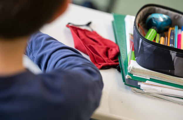 Eine Mund-Nasen-Bedeckung liegt während einer Unterrichtsstunde einer fünften Klasse des Friedrich-Schiller Gymnasiums neben einem Mäppchen und Schulbüchern auf einem Schultisch. Eine Mund-Nasen-Bedeckung liegt während einer Unterrichtsstunde einer fünften Klasse des Friedrich-Schiller Gymnasiums neben einem Mäppchen und Schulbüchern auf einem Schultisch.