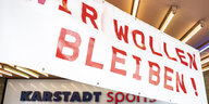 Angestellte von Karstadt-Sports demonstrieren vor der Filiale in Charlottenburg mit einem Banner mit der Aufschrift "Wir wollen bleiben" gegen geplante Schließungen