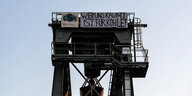 Turm eines Heizkraftwerks - daran ein Banner mit der Aufschrift: Wer uns räumt, ist für Kohle