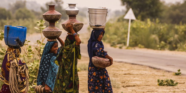 Frauen in Pakistan tragen Wasserbehälter auf dem Kop