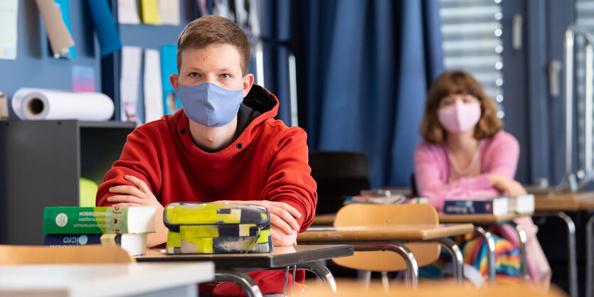 Kinder mit Mundschutz an Schultischen