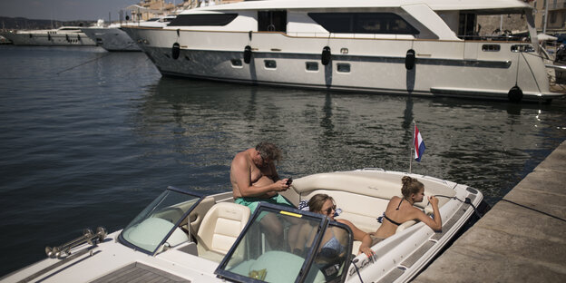 Drei Personen chillen auf einem teuer aussehenden Boot