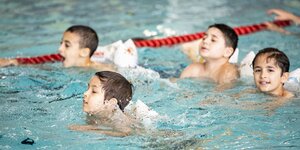Kinder bei ersten Schwimmversuchen im Becken eines Schwimmbads in Berlin