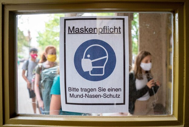 Ein schild weist in einer Schule auf dei Maskenpflicht hin.